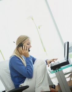 Woman at computer speaking on mobile phone